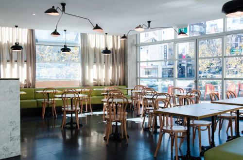 a dining room with tables and chairs and windows at ibis budget Sydney East in Sydney