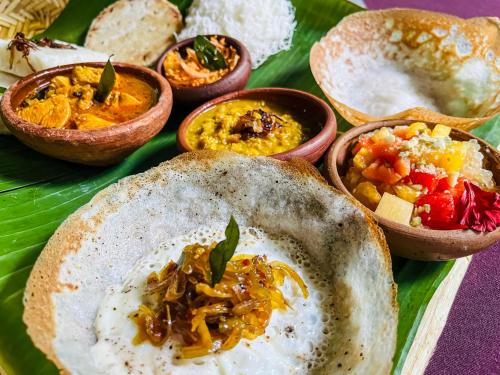 a plate of food with bowls of different types of food at Sundaras Infinity Jungle Resort & Spa in Dambulla