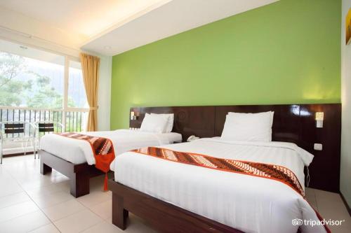 two beds in a room with a green wall at Casa Monte Rosa in Puncak