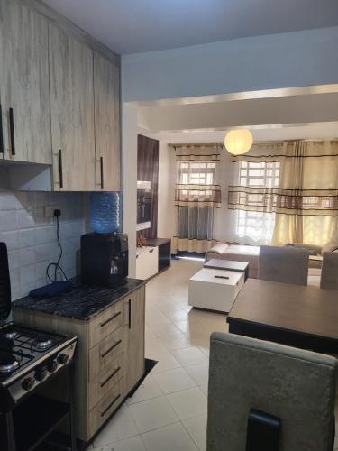 a kitchen and living room with a stove and a couch at Kim's Executive Three bedroom apartment with outdoor, Nakuru CBD in Nakuru