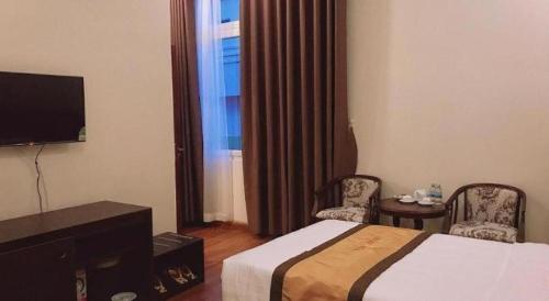 バンメトートにあるLUCKY STAR HOTELのベッドと椅子2脚とテレビがあるホテルの部屋