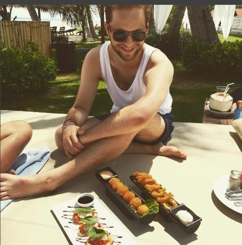 a man sitting on a table with a plate of food at Infinity Beach Club Resort & Hostel Koh Phangan in Baan Tai