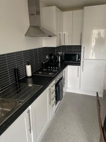 a kitchen with white cabinets and a black counter top at Maison 109 Suite - Modern City Apartment in Glasgow