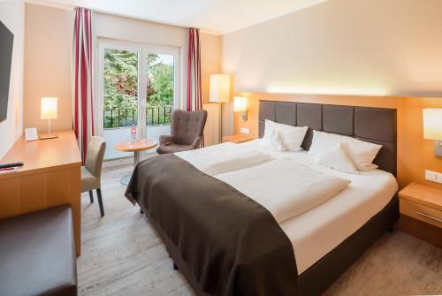 a hotel room with a bed and a desk and a window at Moin Hotel Cuxhaven in Cuxhaven