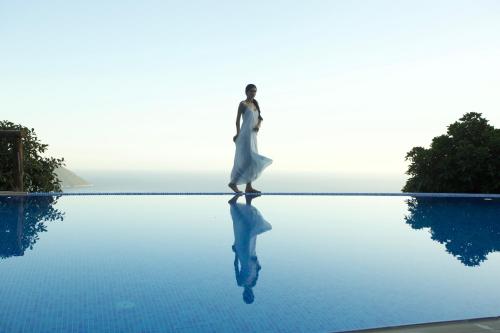 a woman in a white dress walking on a pool of water at Lissiya Hotel in Faralya