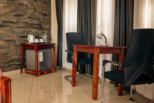 Zimmer mit Stühlen, einem Tisch und einem TV in der Unterkunft Nile Bridge Cottages in Jinja