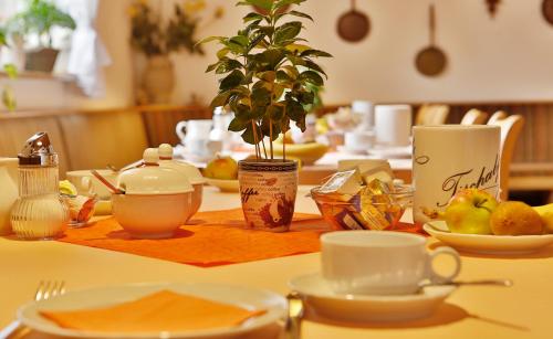 einem Tisch mit Teller und Tassen und einer Pflanze darauf in der Unterkunft Hotel Feuerbacher Hof in Stuttgart