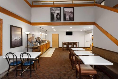 a dining room with tables and chairs and a kitchen at Super 8 by Wyndham Green Bay Near Stadium in Green Bay