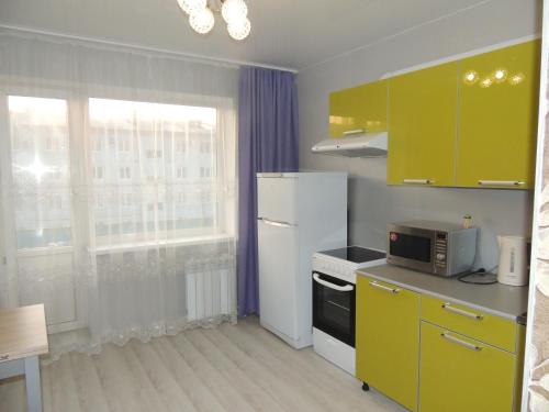 ブラゴヴェシチェンスクにあるApartments on Amurskaya 106のキッチン(黄色のキャビネット、白い冷蔵庫付)