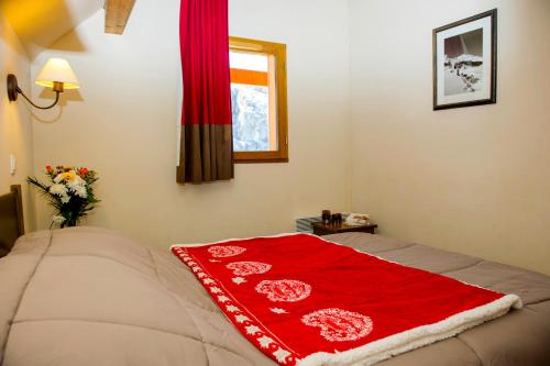 eine rote Decke auf einem Bett in einem Schlafzimmer in der Unterkunft Résidence Goélia Les Chalets Valoria in Valloire
