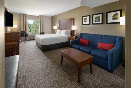 a hotel room with a bed and a blue couch at Wingate by Wyndham Grove City in Grove City