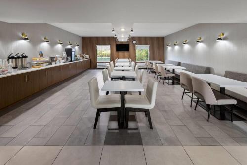 a dining room with white tables and chairs at Wingate by Wyndham Grove City in Grove City