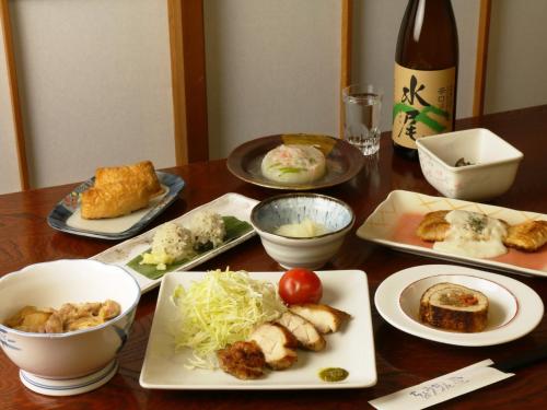 a table with plates of food and a bottle of wine at Chouchinya in Nozawa Onsen