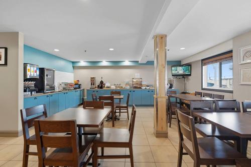 a restaurant with tables and chairs and a kitchen at Country Inn & Suites by Radisson, Saskatoon, SK in Saskatoon