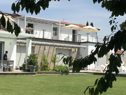 Cette maison blanche dispose d'un balcon avec un parasol. dans l'établissement Dolce Dormire Suite, à Arcola