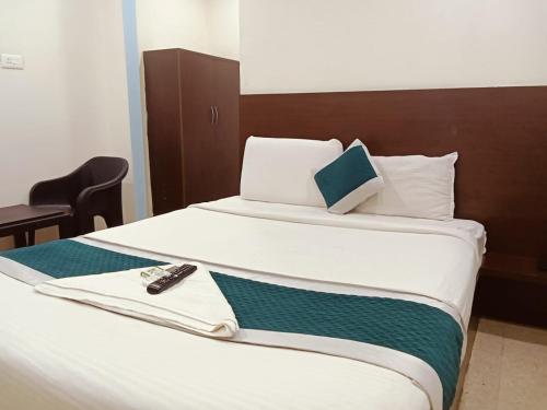 a bed with a remote control sitting on top of it at At Home Hotel Darbar in Hyderabad