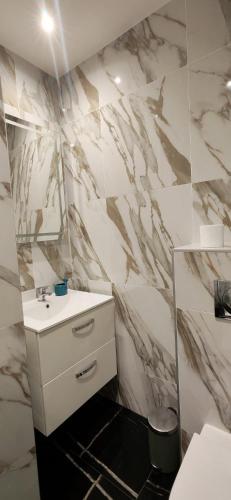 a bathroom with a sink and a marble wall at Bright apartment in Menton in Menton