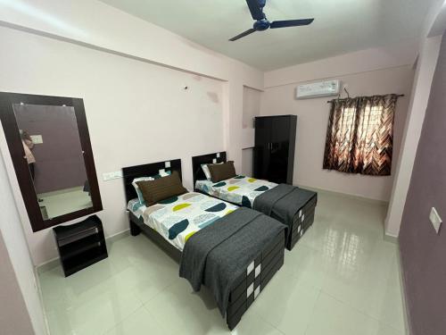 a bedroom with two beds and a mirror at CC Elite Homestay in Hyderabad