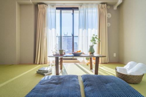 a living room with a table and a large window at Chuan House Dotonbori in Osaka