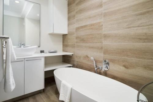 a bathroom with a white tub and a sink at Cosy Regency menylin apartment in Pretoria
