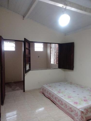 a bedroom with a bed and two windows at Hostel Mangabeira in Cachoeira