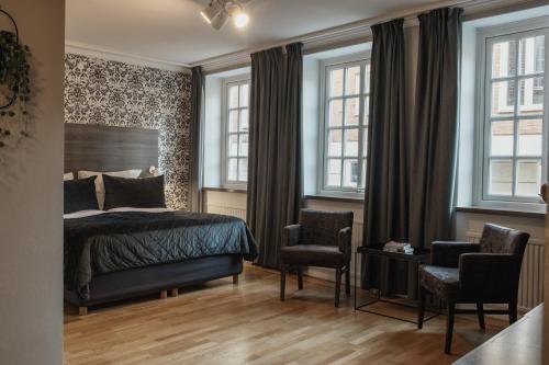 - une chambre avec un lit, 2 chaises et des fenêtres dans l'établissement Home Hotel Grand Helsingborg, à Helsingborg