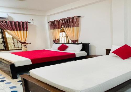 two beds in a room with red and white at Aadhira Guest House in Trincomalee