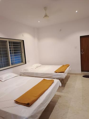 two beds in a room with white walls and a window at Laxmi Residency in Akalkot