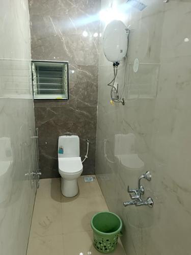 a bathroom with a toilet and a green bucket at Laxmi Residency in Akalkot