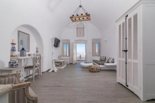 a bathroom with white walls and a large room with white furniture at Angel Luxury Suites in Fira
