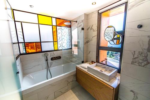 a bathroom with a tub and a sink and a window at Appartement de luxe les Arcs 4 chambres skis aux pieds in Arc 1800