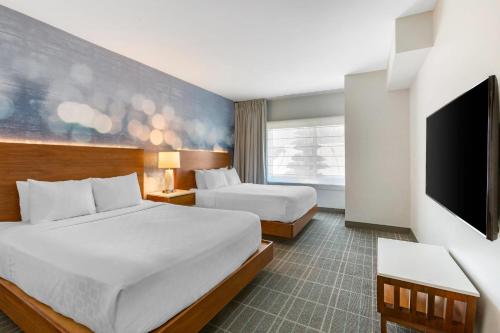 a hotel room with two beds and a flat screen tv at Cambria Hotel LAX in El Segundo