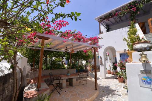 un patio con una mesa y algunas flores rosas en Patmos Maria Studios en Skala