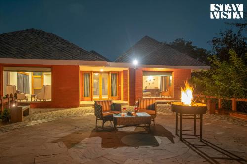 une terrasse avec un foyer extérieur en face d'une maison dans l'établissement StayVista at Petals Of Dusk - Outdoor pool, WiFi & BBQ, à Jaipur