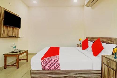 a bedroom with a bed with red pillows and a tv at Collection O Kammasandra Gate Bus Terminal Formerly Riches Inn in Bayappanhalli