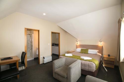 Habitación de hotel con cama y silla en Allan Court Motel, en Dunedin