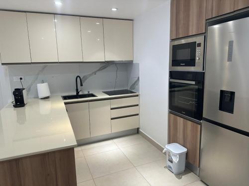 eine Küche mit weißen Schränken und einem Edelstahlkühlschrank in der Unterkunft Apartment f2 in Hydra