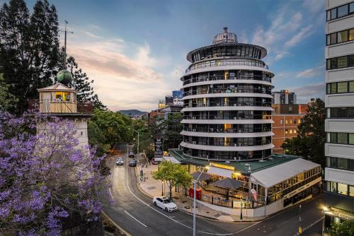a tall building with a clock tower next to a street at Madison Tower Mill Hotel in Brisbane