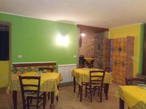 a restaurant with yellow tables and chairs and a green wall at Hotel Sant'Anna in Floresta