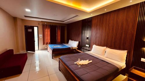 ein Hotelzimmer mit zwei Betten und einer Couch in der Unterkunft Misty Cloud in Devikolam