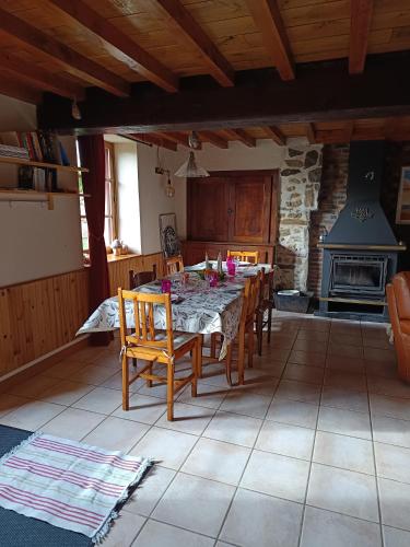 a dining room with a table and chairs and a fireplace at Au repos de la Sioule in Menat