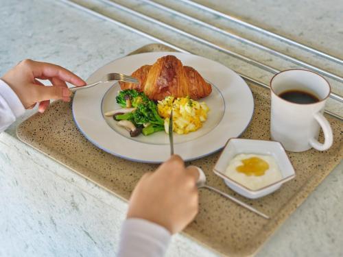 una persona comiendo un plato de comida con huevos y brócoli en Komado ベンガラ, en Komatsu