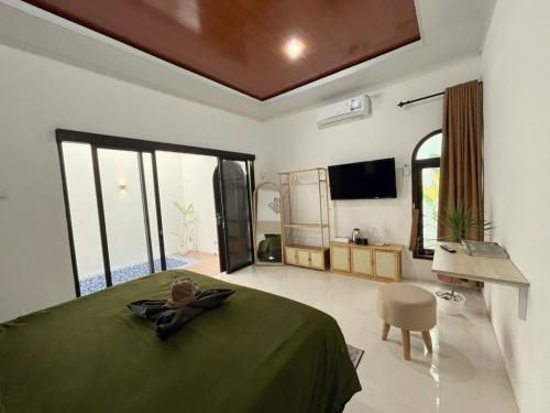 a bedroom with a green bed and a television at Prama Peaceful Living Villa in Ngaglik