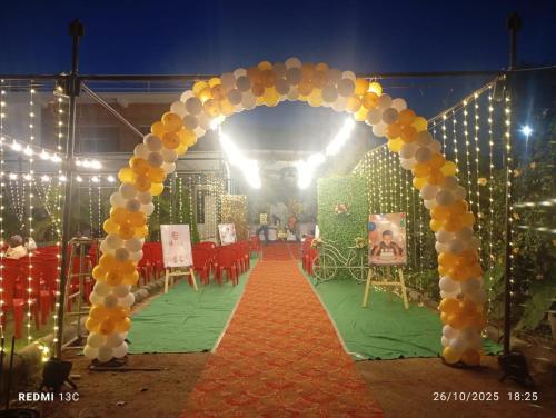 an arch with orange and white balloons on a red carpet at Sai Swastik Homestay Hampi in Munirābād