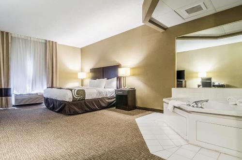 a hotel room with a bed and a tub and a sink at Quality Suites Graham - Burlington South in Graham