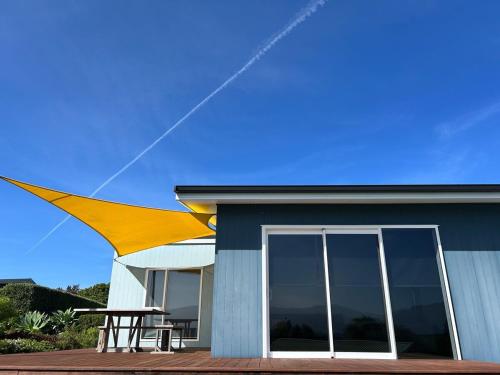 a house with a large yellow umbrella on top of it at Bay Vista - glorious Golden Bay Ocean Views in Pohara