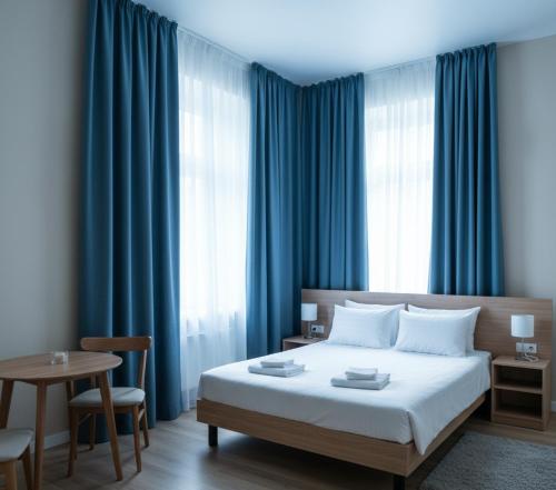 1 dormitorio con 1 cama con cortinas azules y mesa en GozGen Apart, en Alejandreta