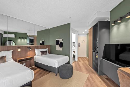 Un dormitorio con dos camas y un televisor de pantalla plana. en Madison Tower Mill Hotel, en Brisbane