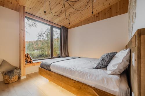 a bedroom with a bed and a large window at River Escape Retreat & Spa - Adults Only in Avrig