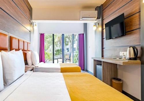 Una habitación de hotel con dos camas y un televisor de pantalla plana. en Maya World Didyma Hotel - Ultra All Inclusive, en Didim